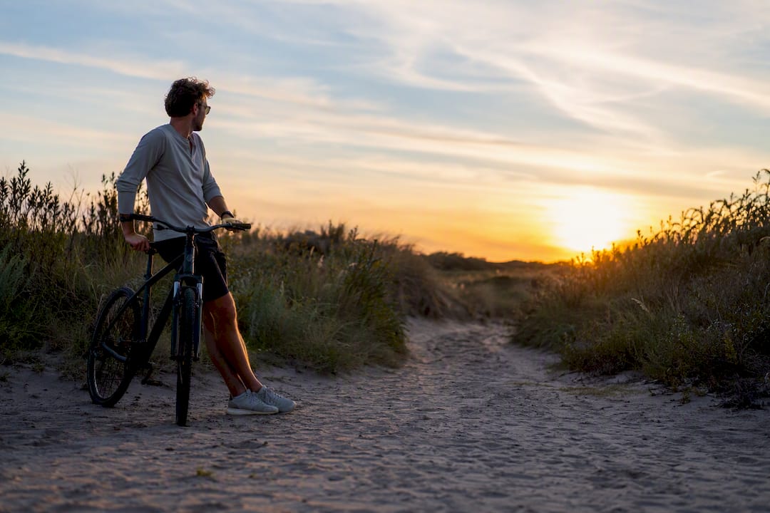 Fietser die zijn fiets afstelt op het duinenpad