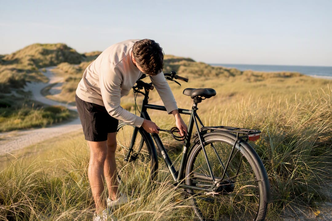 Iemand die zijn fiets op de duinen van Ameland op slot zet