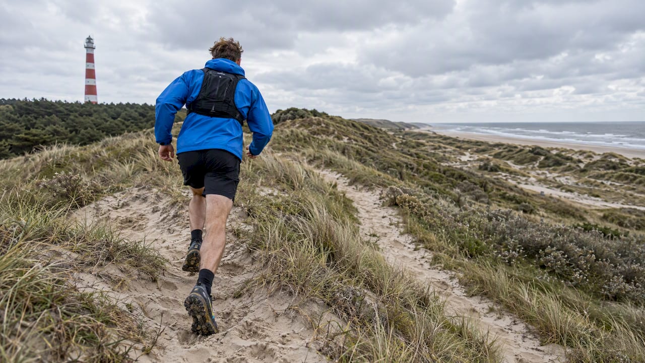 Trailrunner op een duin bij de vuurtoren van Ameland